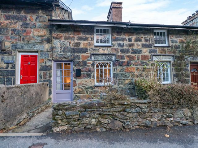Stone cottages with red and gray doors and small front gardens at Riverside Cottage in Beddgelert