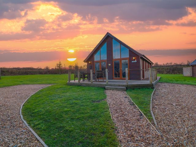 A cabin with a deck and chairs during sunset at Lodge 3 Thorpe-On-The-Hill