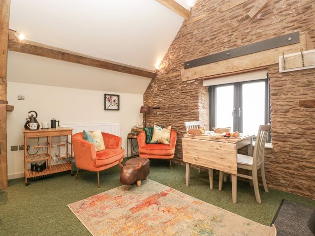 A room with two orange chairs a small wooden dining table with two chairs a wooden trolley and a decorative ottoman at Palace Studio in St Weonards