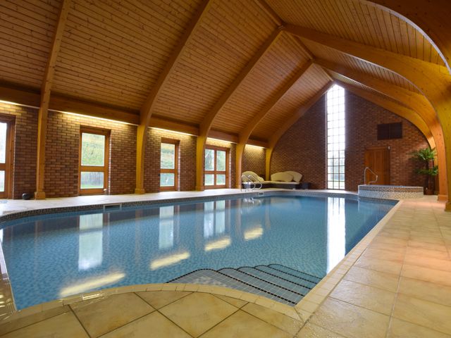 An indoor swimming pool with steps leading into the water wooden arched ceiling brick walls and lounge chairs at Solway in Chester
