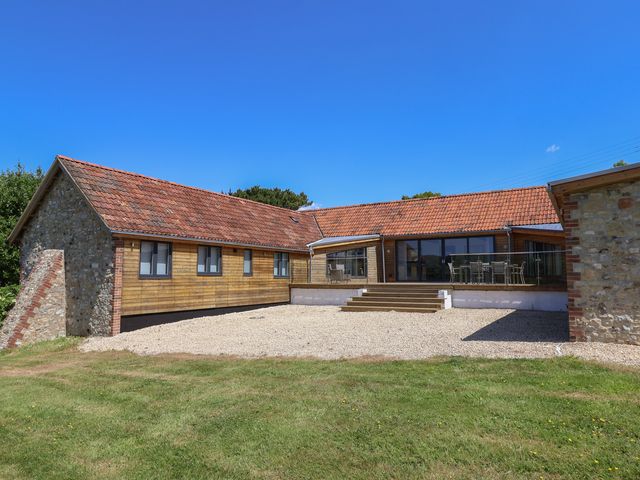 A house with a deck and yard at The Stables in Uplyme