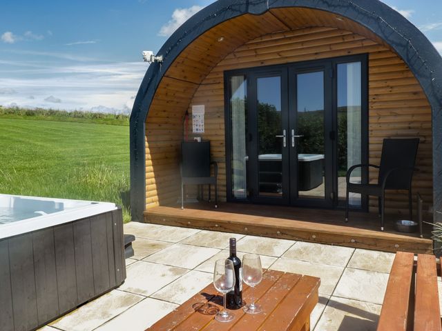 An outdoor area with a hot tub and seating at Holly in Ulverston