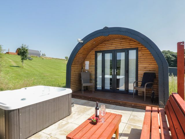 An outdoor area with a hot tub and wooden cabin at Rowan in Ulverston