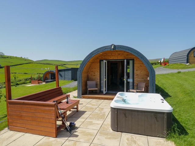 An outdoor area with a hot tub and wooden bench at Cherry in Ulverston
