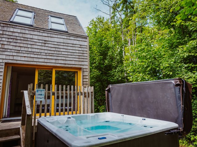 A hot tub on a wooden deck outside a house with shingle siding and two skylights at Lodge 15 in Corfe Castle