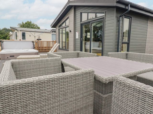 An outdoor seating area with wicker chairs and a table next to a grey building at Mordros Lodge in St Day