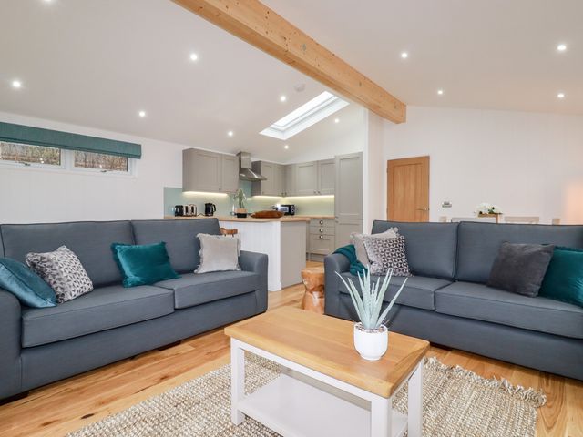A living room with two sofas a coffee table and a kitchen in the background at 7 Valley View in Lanreath