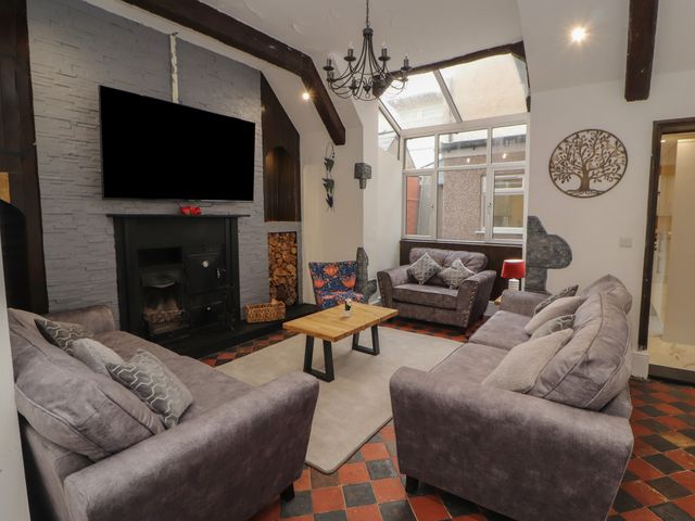 A living room with three sofas a wooden coffee table a fireplace and a large window at The Furness Haven in Barrow-In-Furness