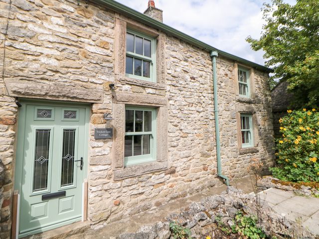 A stone cottage with a front door and windows at Trickett Gate Cottage in Castleton, Peak District