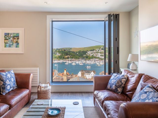 A living room with two leather sofas and a large window overlooking a harbor with boats and hills at 44 Above Town in Dartmouth