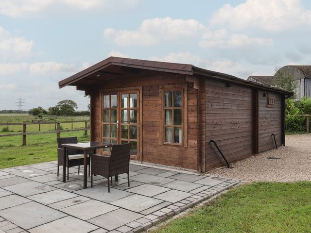 A wooden cabin with outdoor seating and patio at Lodge 1 in Strensall
