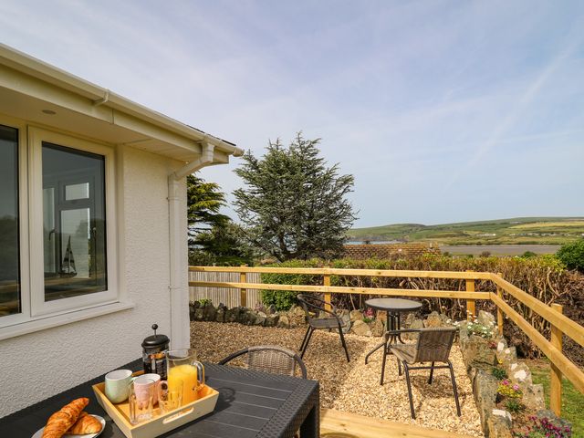 A patio with a table set with croissants juice and cups and a gravel area with two small tables and chairs outside Bryn Alaw in Newport Pembrokeshire