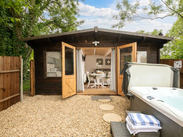 An outdoor view of a garden with a hot tub and a cabin at Hazel in Blandford Forum