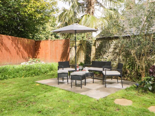 A garden patio area with outdoor furniture and an umbrella at Harmony House in Bere Alston