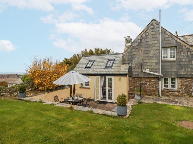 An outdoor seating area with a table and chairs at Ivy Cottage in Trenale near Tintagel
