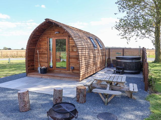 A wooden pod cabin with a picnic table fire pit and hot tub outside at Bouquet in Little Kelk near Bridlington