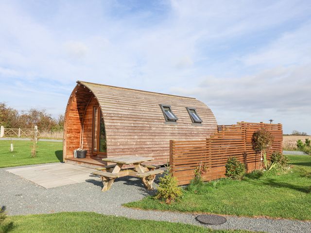 A small wooden curved cabin with a picnic table and a wooden fence in a grassy area at Parliament in Little Kelk near Bridlington