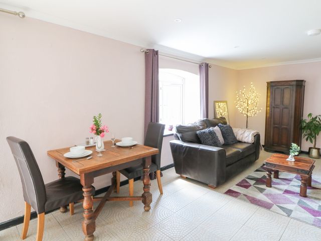 A living room with a dining table and a sofa at Garden apartment in Llandysul