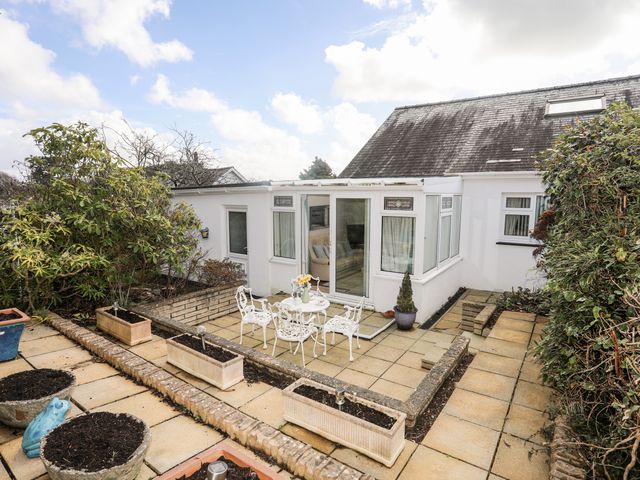 An outdoor patio area with a white table and chairs and planter boxes at Berllys in Criccieth