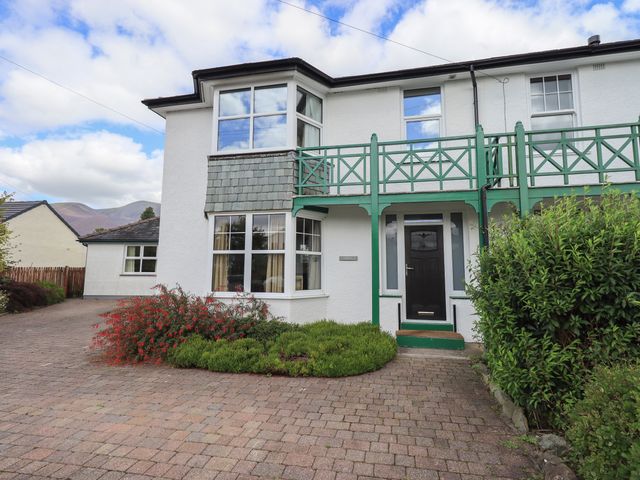 The exterior of a white two-story house with green balcony and plants in front at Limhus House in Keswick