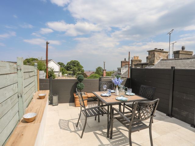 An outdoor patio area with a dining table and chairs set with glassware and flowers at Brigwyn in Nefyn