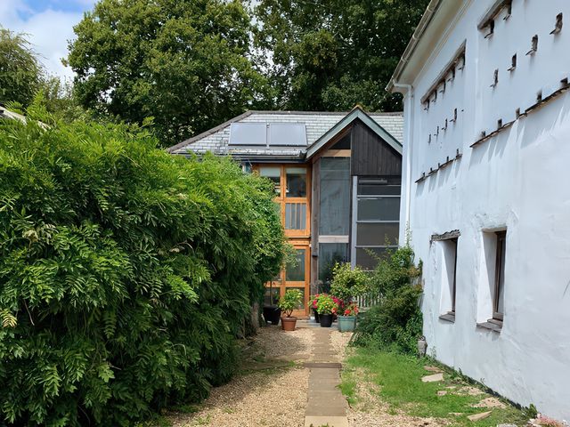 A garden with a pathway between buildings at Barberry Brook in Dittisham
