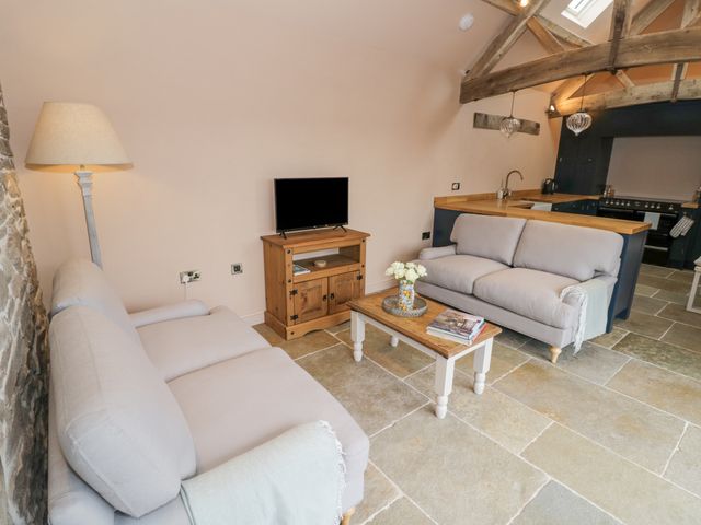 A living room with two sofas a wooden coffee table TV on a stand and part of a kitchen at Meadow Barn in Pudleston near Leominster