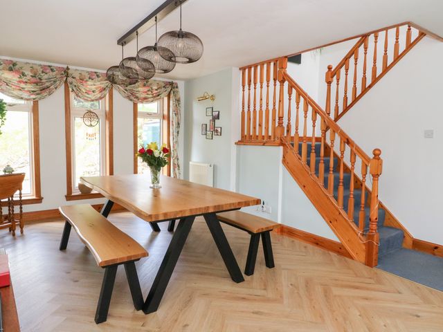 A dining area with a wooden table and benches near a staircase in Ninevah Auchtubh near Strathyre