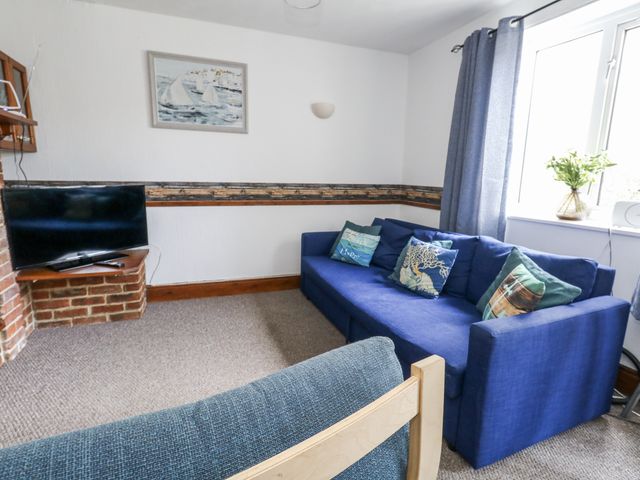 A living room with a blue sofa and television at Saddlers Cottage in Weymouth