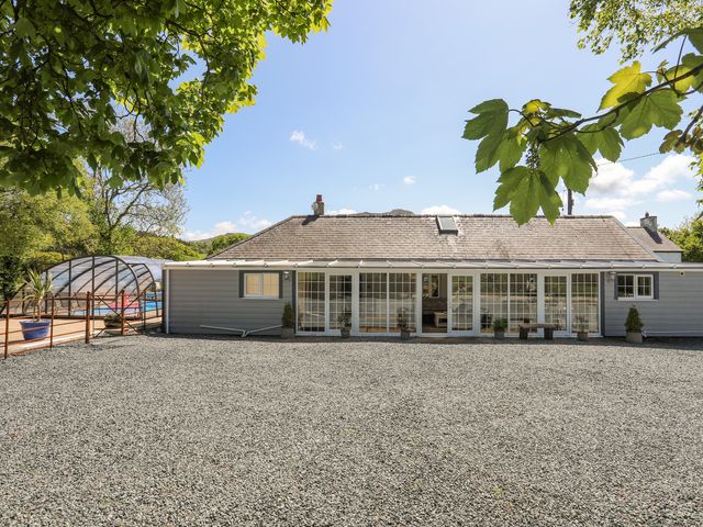 An outdoor view of a single story house with large glass doors and windows and gravel ground at The Keepers Lodge in Boduan near Nefyn
