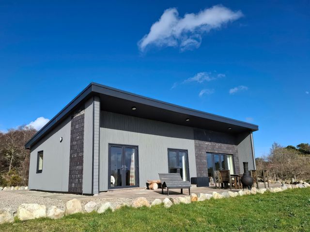 A modern building with windows and patio furniture at Red Squirrel in Dornoch