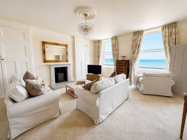 A living room with a sofa, chair, coffee table and television at 123 On The Sea – Victoria’s Place in Weymouth