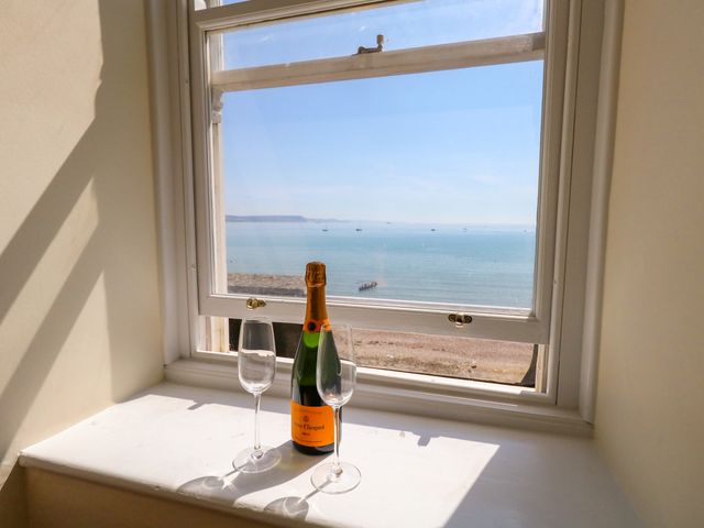 A window with champagne and glasses overlooking the sea at 123 On The Sea – The Eaves in Weymouth