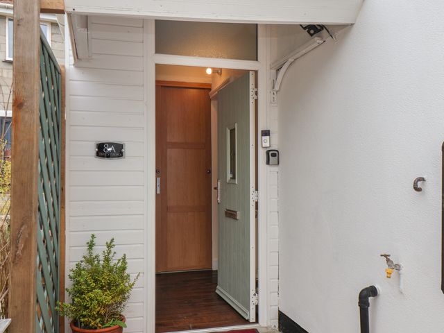 An open front door with a wooden door inside and a potted plant outside at The Studio in Cayton
