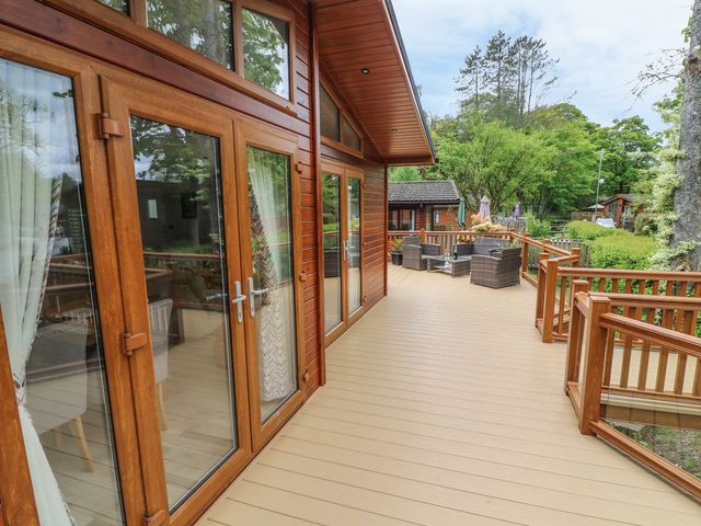 A wooden deck with patio furniture and glass doors at 8 Waterside Wood in White Cross Bay near Troutbeck Bridge