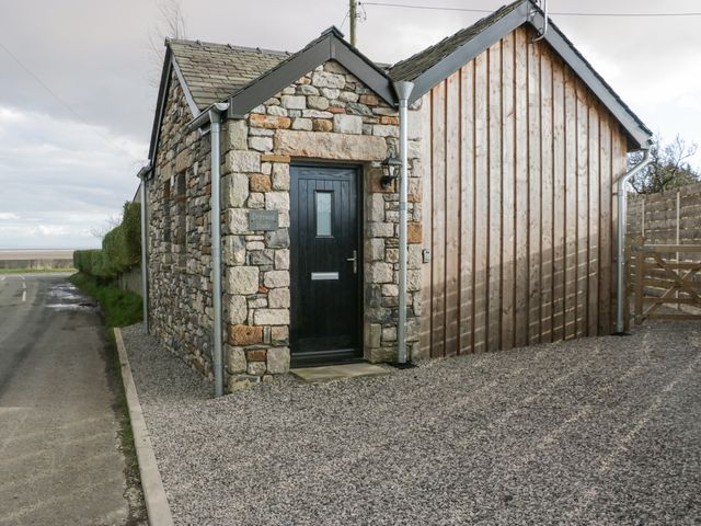 Exterior of a stone and wooden building with a black door and gravel driveway at Driftwood Studio in Goadsbarrow near Barrow-In-Furness