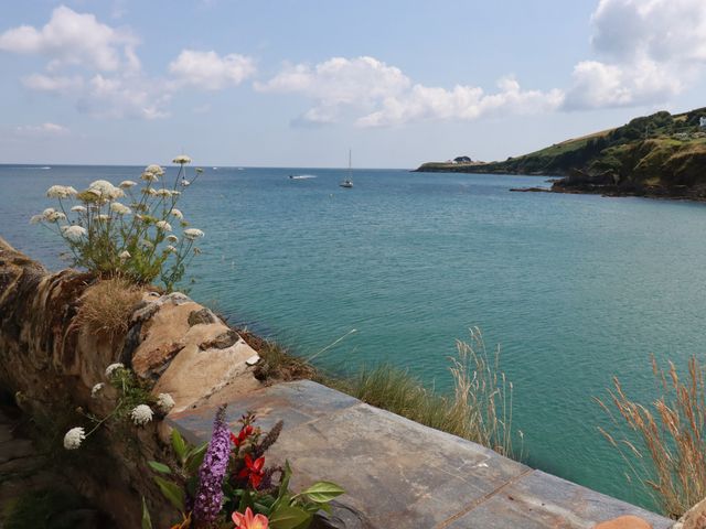 A coastal view with flowers on a stone wall overlooking the sea at Chy Rani in Portmellon near Mevagissey