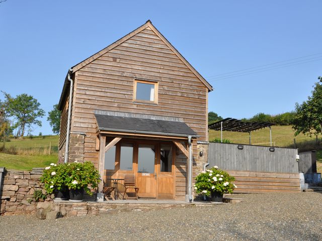 A house with a wooden exterior and gravel driveway at Rockhill Farm Hay Barn in Clun