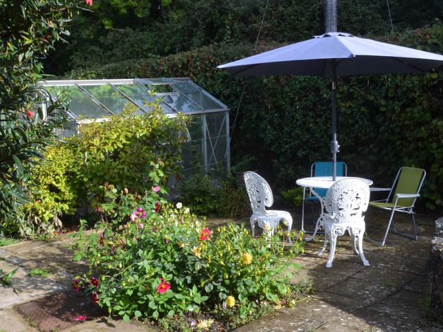 A garden with flowers and a table under an umbrella at Woodstock in Chard