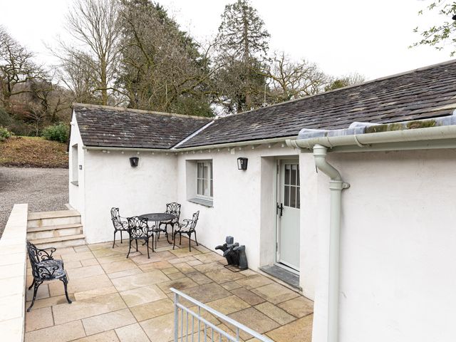 A patio area with a metal table and chairs and a bench outside a white building at The Bothy in Newby Bridge