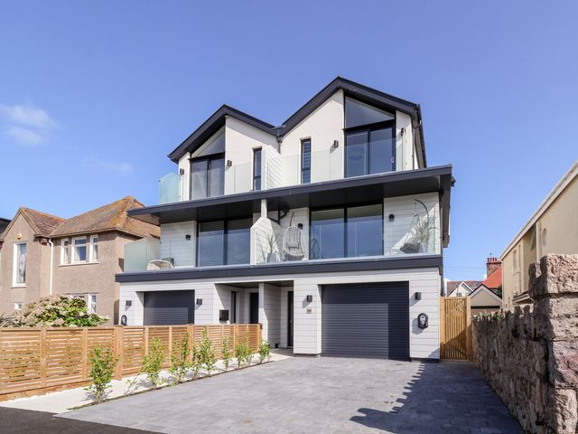 A modern three-story house with balconies and garages at The Dunes in Llandudno