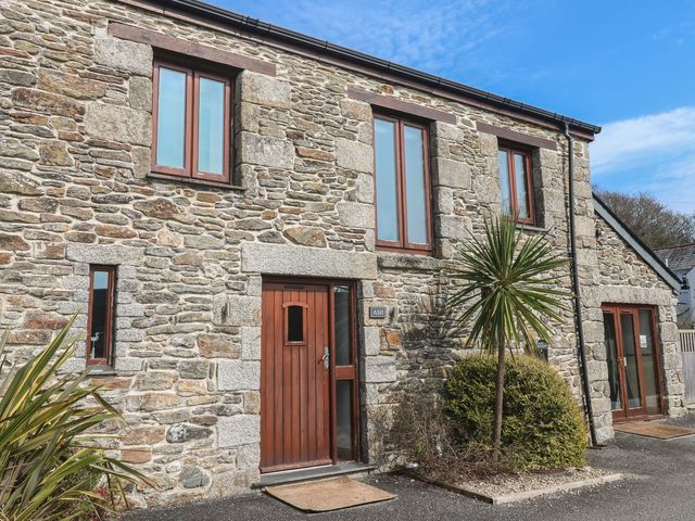 A stone house exterior with windows and a door at Ash Barn in Falmouth