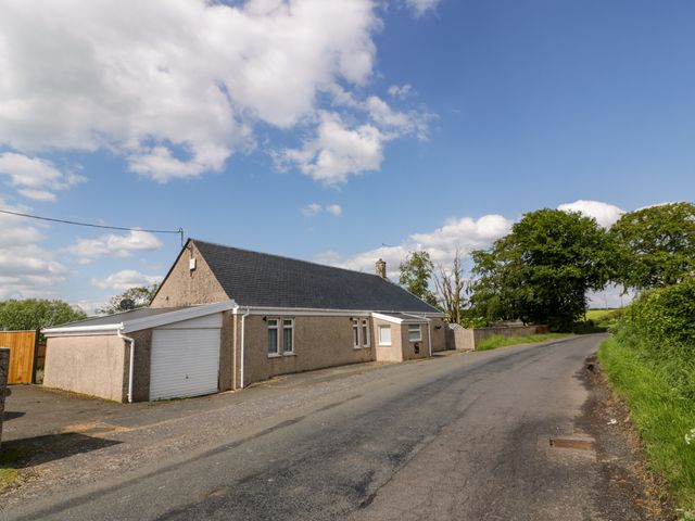 A bungalow with a garage along a rural road with trees and grass in the background at Largieholm in Mauchline