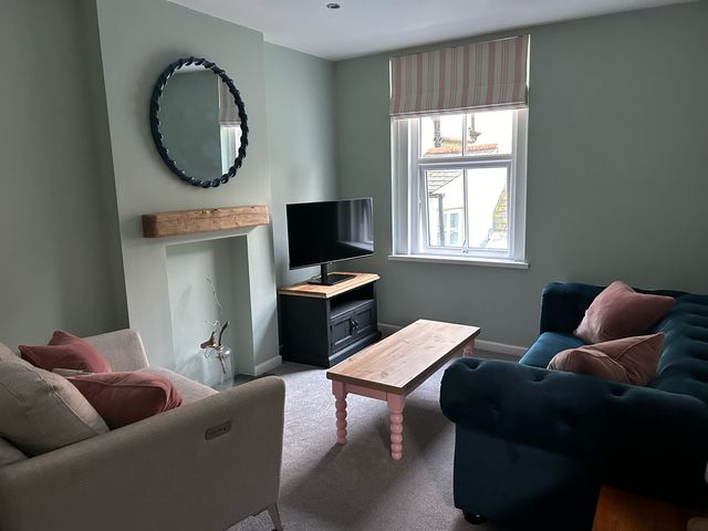 A living room with sofas a coffee table a television on a stand and a window at Secret Garden 34C Clarence Street Dartmouth