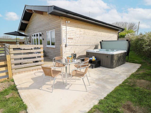 An outdoor area with a hot tub and seating at Monks Rest in Monknash