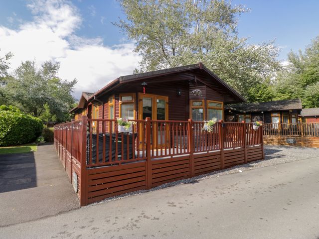 A lodge with a wooden deck and fence at Ruskin Lodge, Langdale 16, White Cross Bay near Windermere