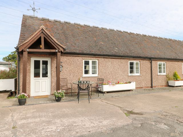 An outdoor area with a table and chairs in front of a house at The Hereford Lodge in Great Haywood