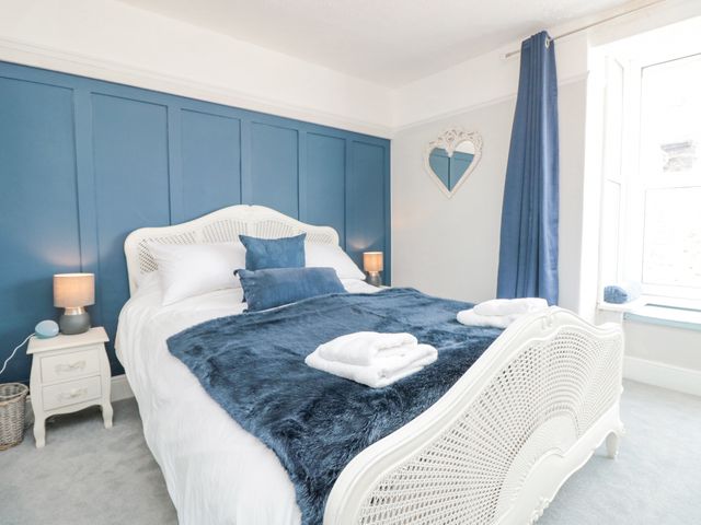 A bedroom with a white bed blue pillows blue throw and a blue accent wall at 8 Above Town in Dartmouth