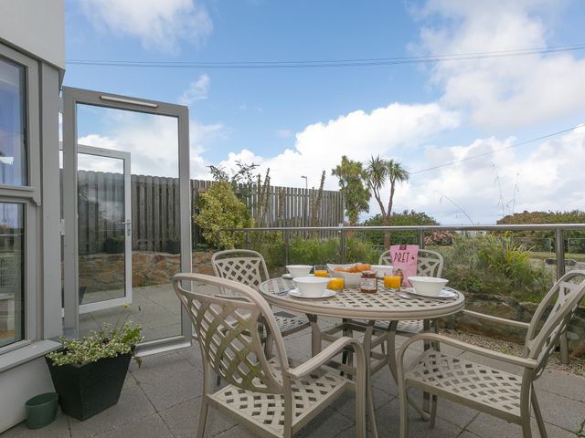 An outdoor patio with a round table and four chairs set with bowls and glasses at 2 Four Seasons in Carbis Bay