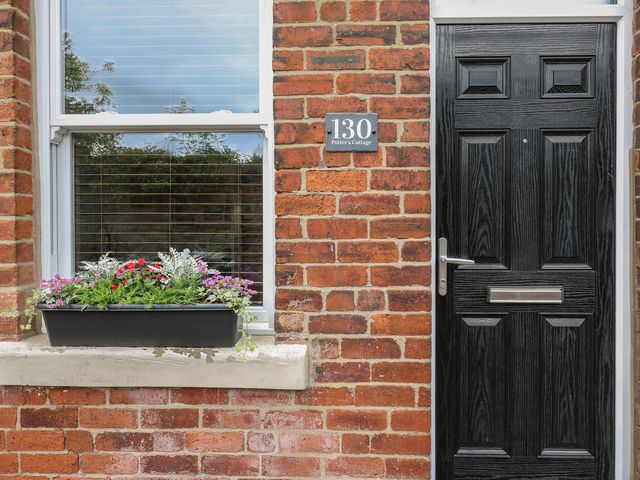 A front door with a window and flower box at Potter’s Cottage in Fulwood near Sheffield